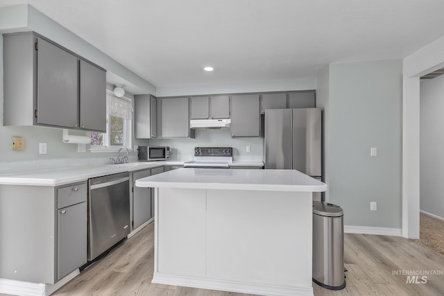 kitchen with gray cabinetry, stainless steel appliances, light wood finished floors, and under cabinet range hood