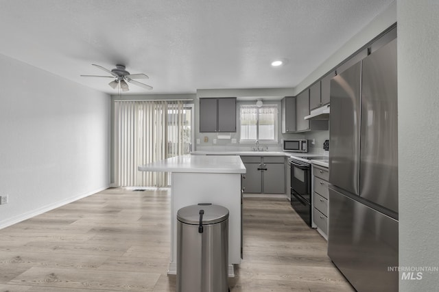 kitchen featuring light countertops, under cabinet range hood, a ceiling fan, gray cabinetry, and stainless steel appliances