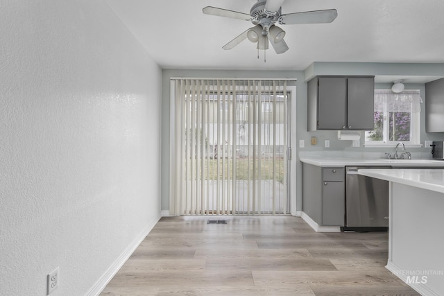 kitchen with a sink, light countertops, gray cabinets, stainless steel dishwasher, and visible vents