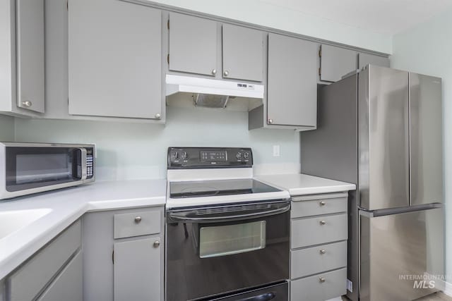 kitchen with gray cabinetry, light countertops, stainless steel appliances, and under cabinet range hood