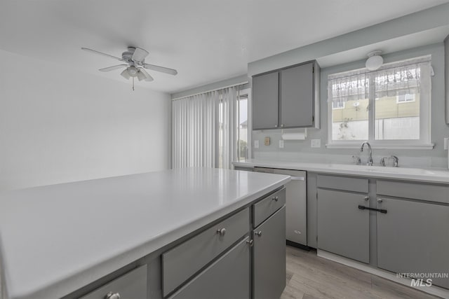 kitchen with gray cabinets, ceiling fan, dishwasher, light countertops, and light wood finished floors