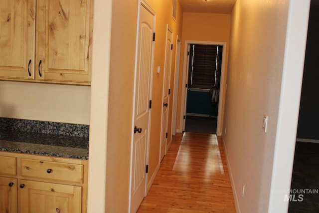 corridor featuring baseboards and light wood-type flooring