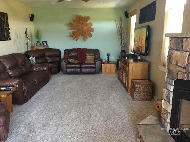 living area featuring a fireplace, carpet, and a ceiling fan