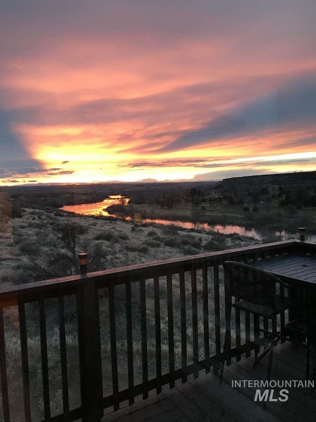 deck at dusk featuring a water view