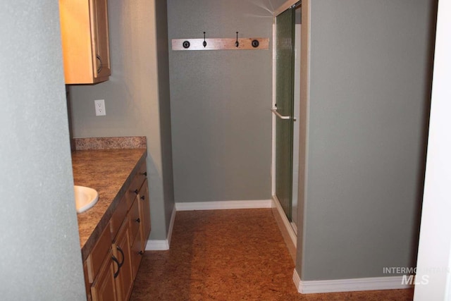 bathroom with vanity, baseboards, and a shower stall