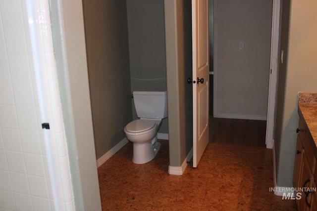 bathroom with baseboards, toilet, and vanity