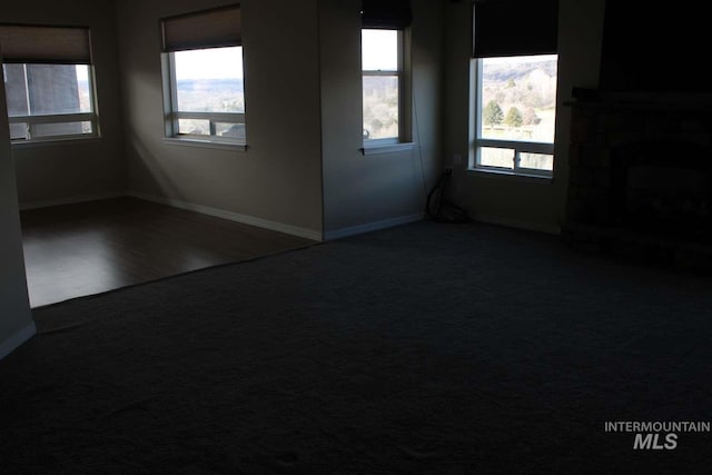 carpeted spare room with baseboards and a fireplace