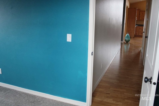 corridor featuring baseboards and wood finished floors