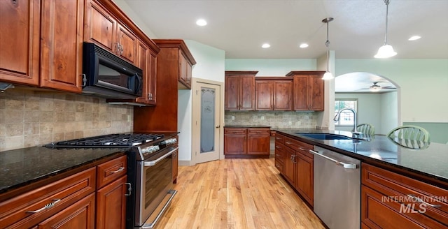 1563 W Colville Ct, Eagle, ID 83616 - kitchen featuring appliances with stainless steel finishes, light wood-style floors, a ceiling fan, dark stone countertops, and pendant lighting