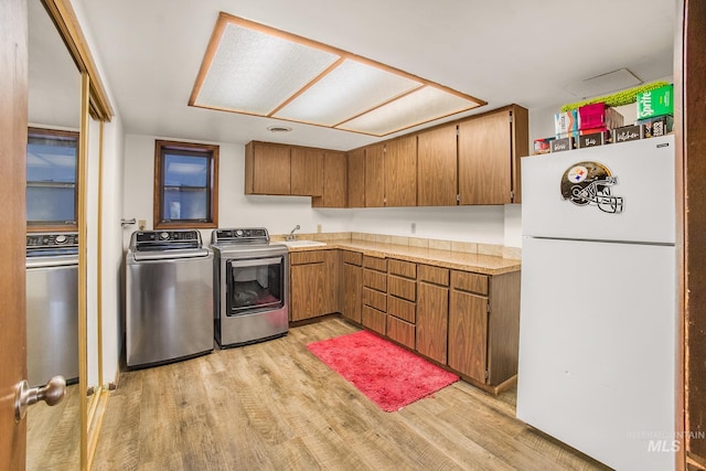 kitchen featuring light wood-type flooring, freestanding refrigerator, brown cabinets, and separate washer and dryer