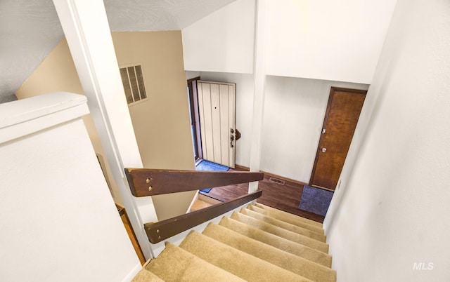 stairs with baseboards, visible vents, and wood finished floors