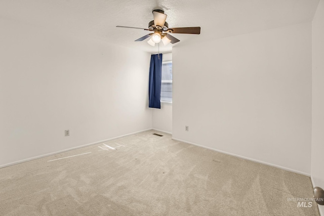 carpeted spare room featuring a ceiling fan, baseboards, and visible vents