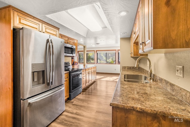 kitchen with stainless steel appliances, recessed lighting, a sink, and light wood-type flooring