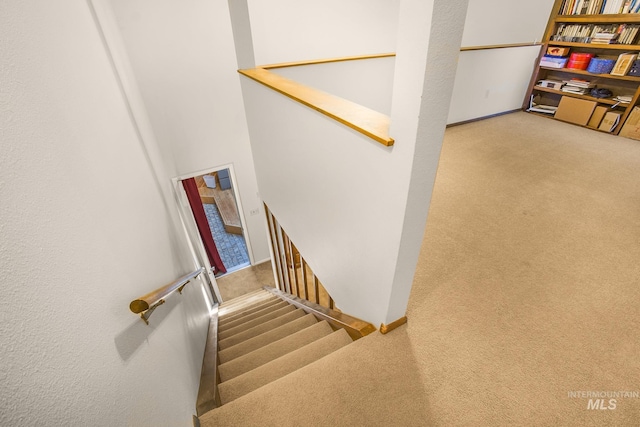 stairway with baseboards and carpet flooring