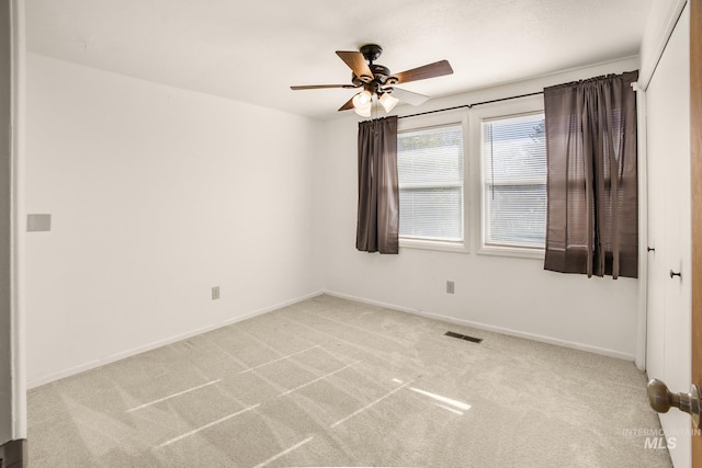 carpeted spare room with ceiling fan, visible vents, and baseboards