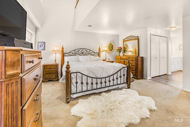 bedroom featuring light colored carpet, connected bathroom, baseboards, and a closet