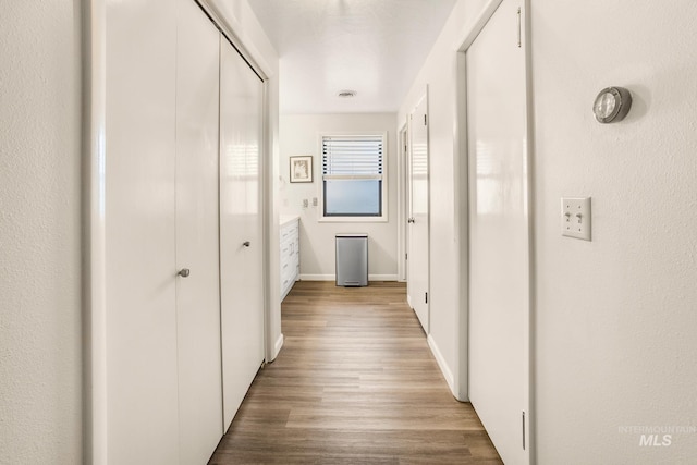 corridor featuring baseboards and wood finished floors