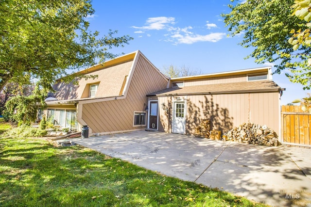 rear view of house with fence, a shingled roof, a yard, and a patio area
