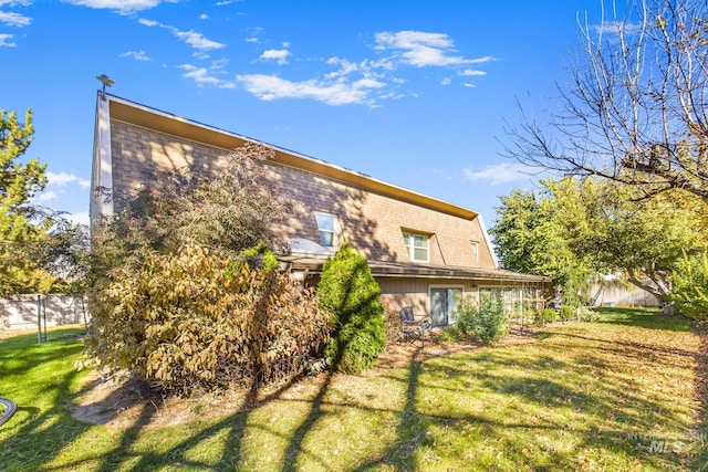 back of property featuring fence and a yard