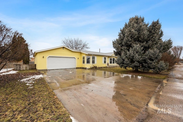 ranch-style house featuring a garage, driveway, and fence