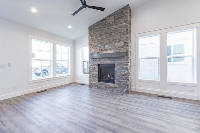 unfurnished living room featuring lofted ceiling, a stone fireplace, light wood-type flooring, and visible vents