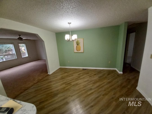 interior space featuring ceiling fan with notable chandelier, dark wood-type flooring, and a textured ceiling