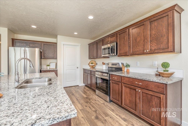 19118 Ralston Way, Caldwell, ID 83605 - kitchen featuring appliances with stainless steel finishes, light wood finished floors, light stone counters, recessed lighting, and a textured ceiling