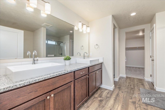 19118 Ralston Way, Caldwell, ID 83605 - bathroom featuring a stall shower, double vanity, a textured ceiling, wood finished floors, and a spacious closet