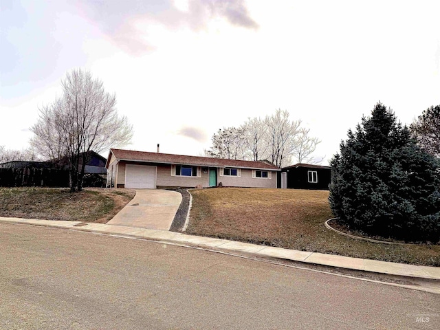 single story home with driveway, an attached garage, and a front yard