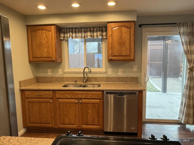 kitchen featuring dishwasher, recessed lighting, brown cabinets, wood finished floors, and a sink