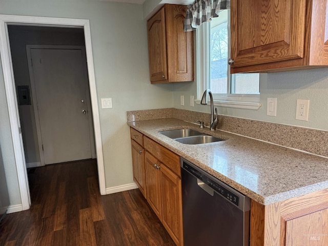 kitchen featuring brown cabinetry, baseboards, a sink, dark wood-type flooring, and dishwasher