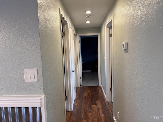 hall with wood finished floors, baseboards, and a textured wall