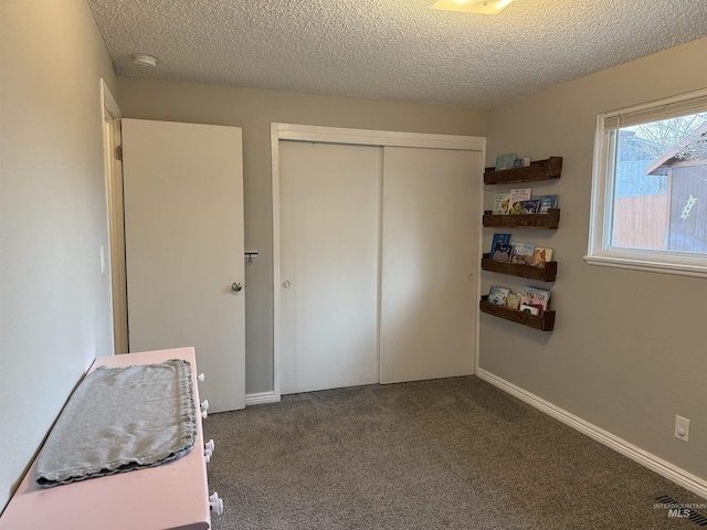 unfurnished bedroom with carpet flooring, baseboards, a closet, and a textured ceiling