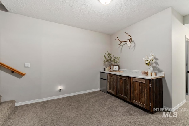 interior space featuring stainless steel refrigerator, light carpet, dark brown cabinets, and a textured ceiling