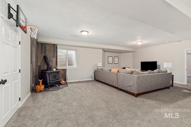 living room featuring carpet flooring, a wood stove, and a textured ceiling