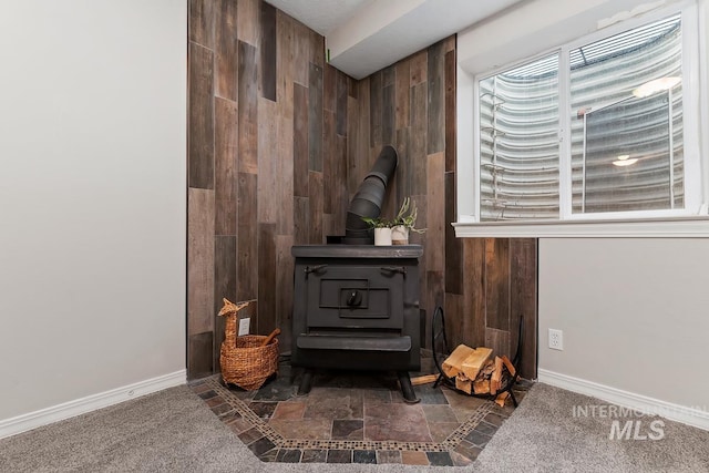 interior details featuring wood walls, a wood stove, and carpet floors