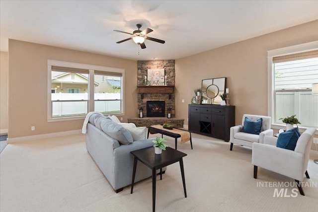living area with plenty of natural light, a fireplace, light colored carpet, and ceiling fan