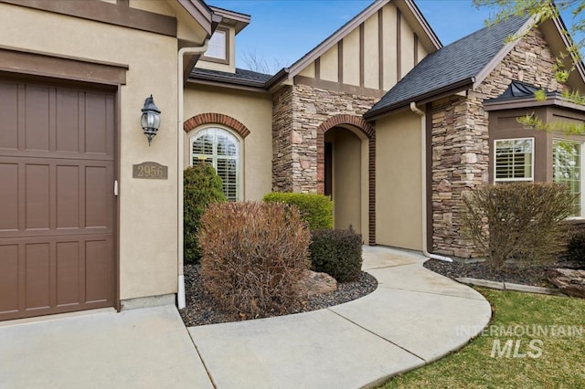 doorway to property featuring stucco siding, stone siding, and an attached garage