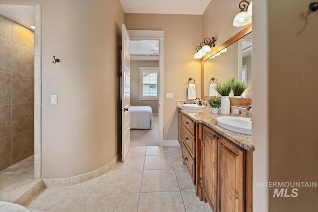 ensuite bathroom featuring tile patterned flooring, double vanity, baseboards, and a sink