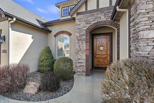 view of exterior entry featuring stucco siding and stone siding