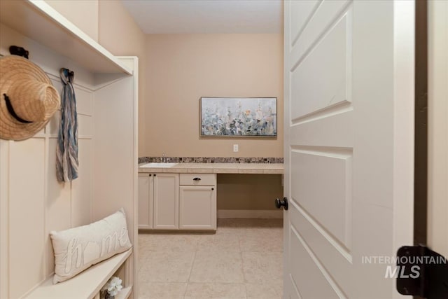 mudroom featuring built in study area, light tile patterned floors, and a sink