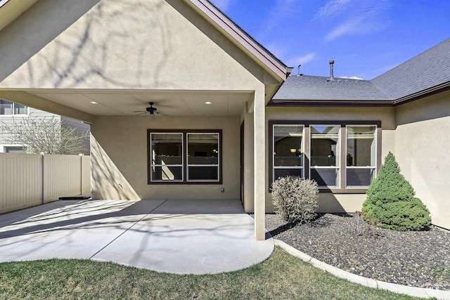 exterior space featuring a shingled roof, a patio area, ceiling fan, fence, and stucco siding