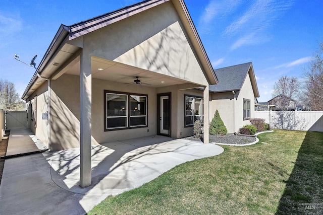 rear view of house featuring fence, a patio, stucco siding, and a ceiling fan