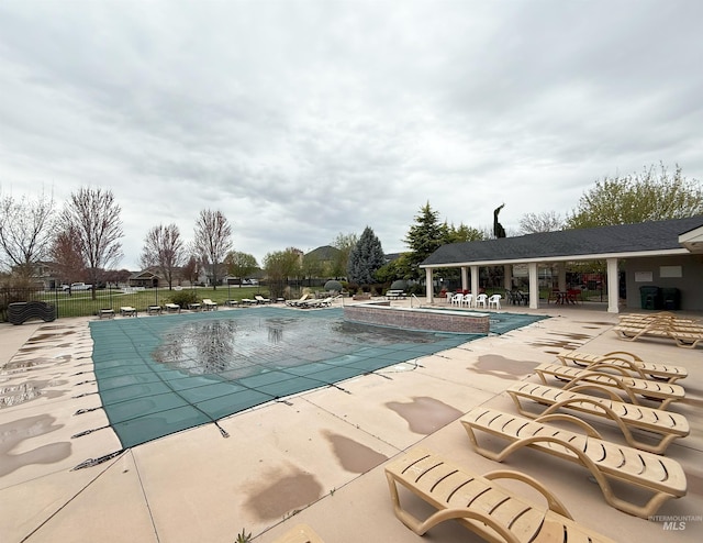 community pool with a patio area and fence