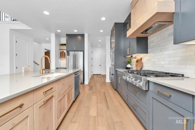 7060 E La Cuesta St, Boise, ID 83716 - kitchen with a sink, appliances with stainless steel finishes, premium range hood, light wood-style flooring, and light countertops