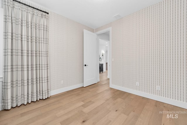 7060 E La Cuesta St, Boise, ID 83716 - unfurnished bedroom featuring wood finished floors, baseboards, and wallpapered walls