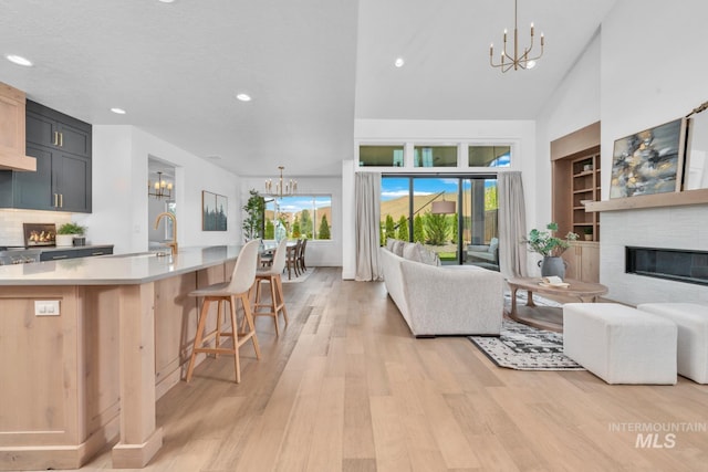 7060 E La Cuesta St, Boise, ID 83716 - living area with a chandelier, a glass covered fireplace, light wood-type flooring, recessed lighting, and a towering ceiling