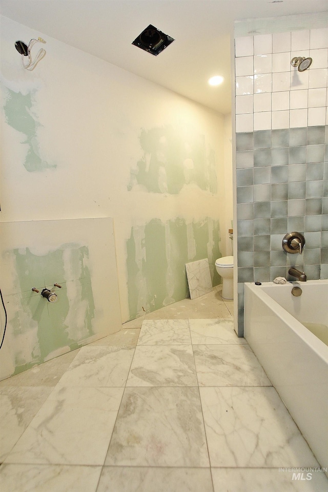 bathroom featuring a tub to relax in, marble finish floor, and toilet