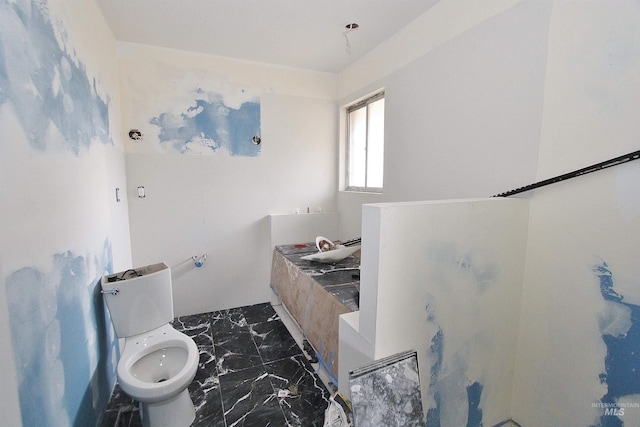 full bathroom featuring marble finish floor and toilet