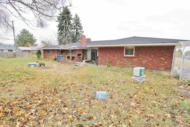 back of house with a yard, brick siding, a chimney, and fence